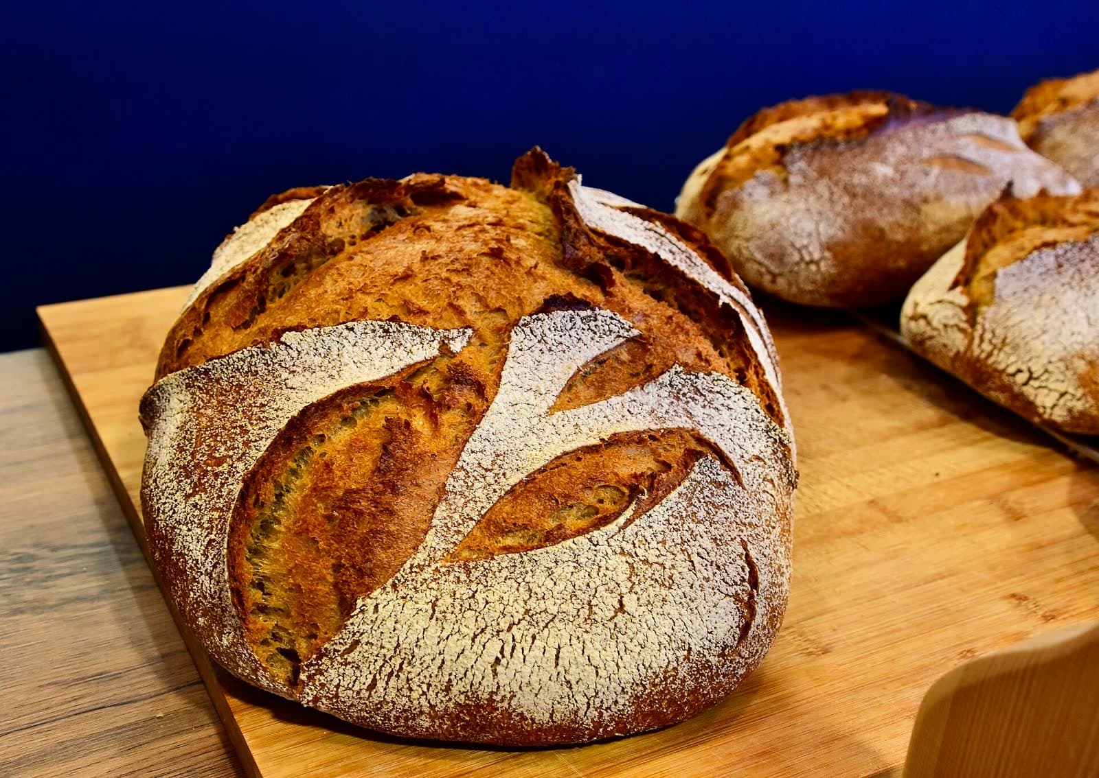 Pains de campagne à la croûte farinée posés sur une planche en bois.